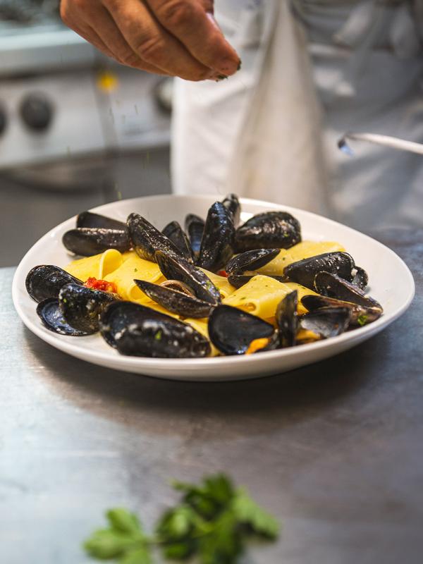 Piatto di pasta con cozze, condito con prezzemolo fresco.